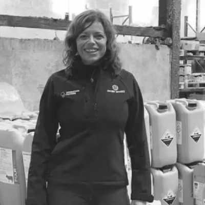 Kathryn Kenneally stands beside stacked livestock feeder containers.